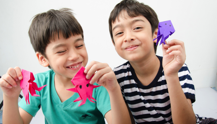 Two brothers, one sighted and one blind, working on origami together.