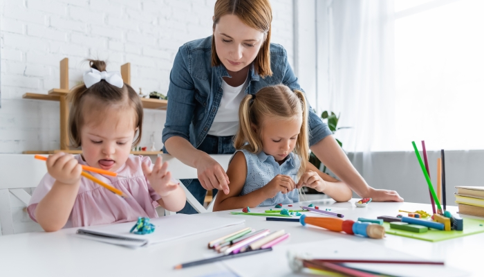 Teacher near preschooler girl and disabled child with down syndrome.