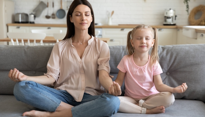 Adult parent mother and little child daughter doing yoga exercise.