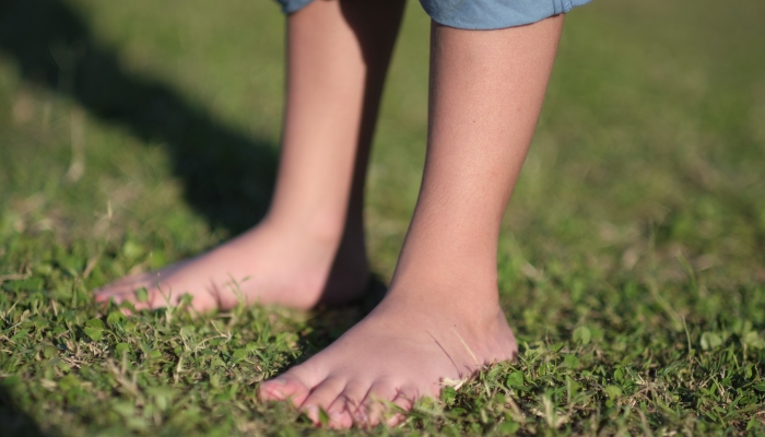 Barefoot little boy enjoying the soft grass beneath his feet on a sunny day.