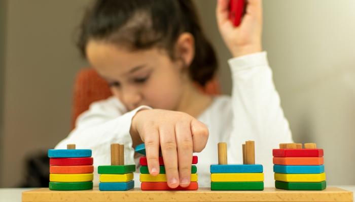 Beautiful blind girl sorts geometric shapes.