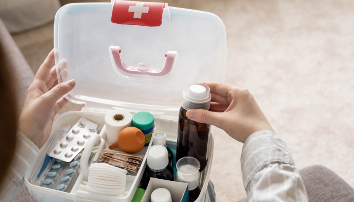 Closeup female hand neatly placing medicament at domestic first aid kit.