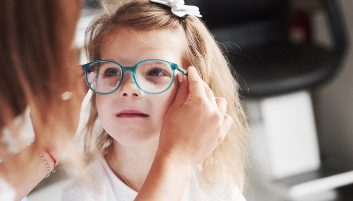 Doctor giving the child new glasses for her vision.