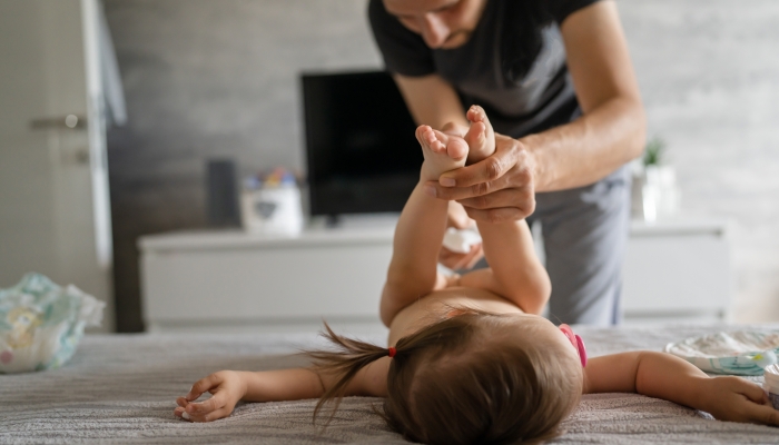 Father changing diapers his daughter toddler girl at home in bedroom.