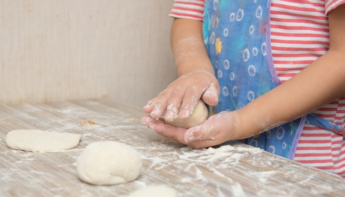 Four-year girl prepares pies with cabbage in the kitchen.