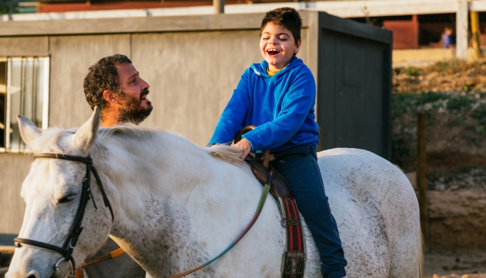 Happy boy with visual impairment riding a horse.