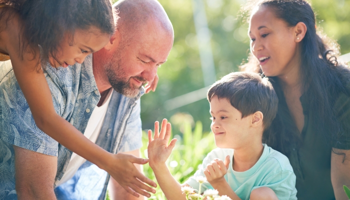 Happy family bonding, high-fiving and planting flowers in summer garden.