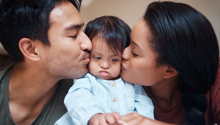 Love, disability and down syndrome parents kiss special needs kid with appreciation.