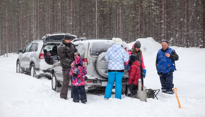 Many people family stops vehicles on winter road to rest.