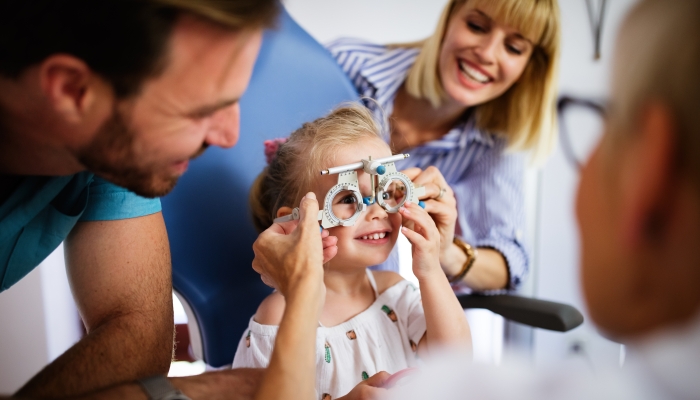 Ophthalmologist is checking the eye vision of little cute girl in modern clinic.