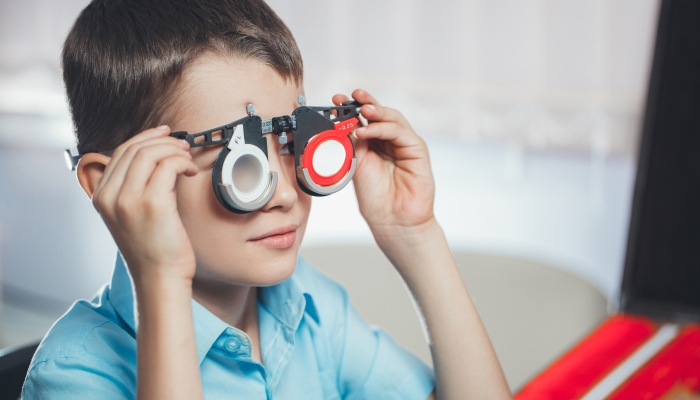 Optometrist picks up glasses for correction of myopia boy.