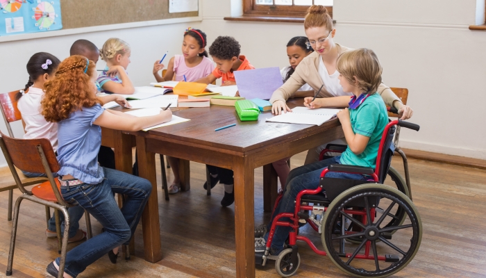 Pretty teacher helping pupils in classroom at the elementary school.