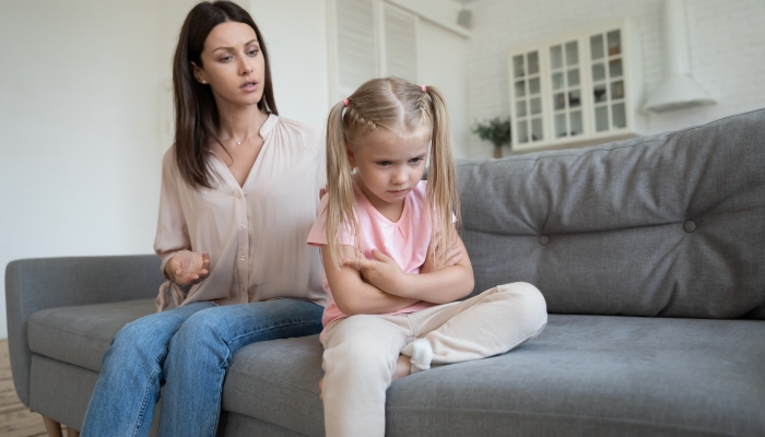 Sad stubborn little girl sit on couch.