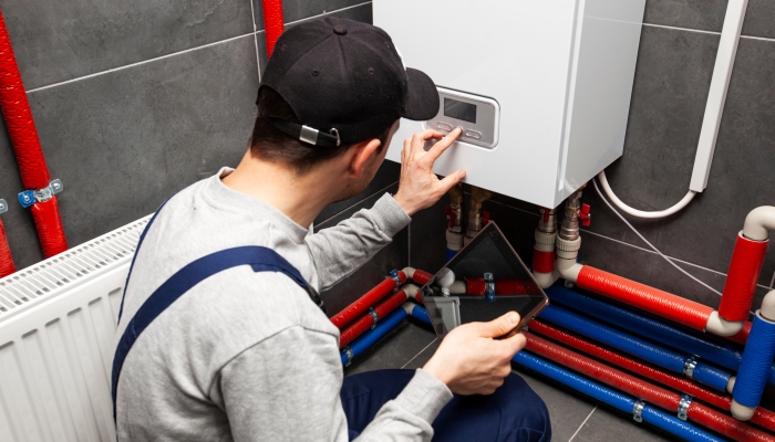 The technician checking the heating system in the boiler room with tablet in hand.