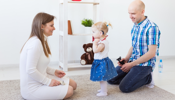 Toddler child wearing a hearing aid at home.