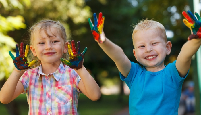 Two adorable kids with hands covered in paint.