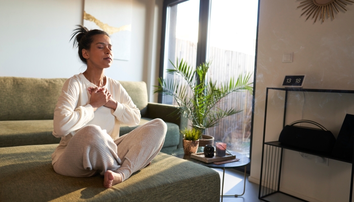 Woman meditating at home with eyes closed.