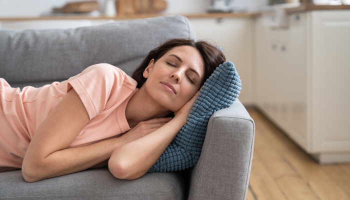 Young mom lying on on pillow on couch.