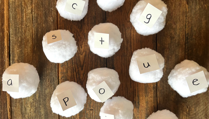 CVC word snowball toss game balls labeled with letters.