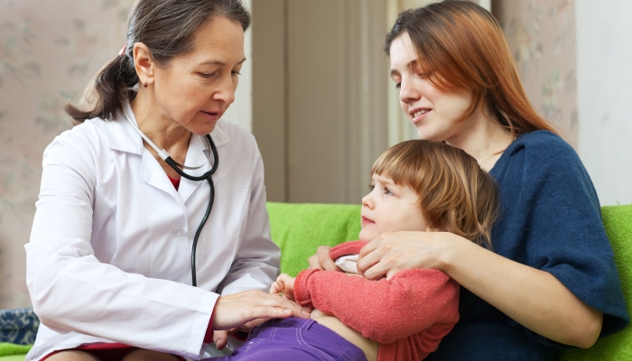 Friendly mature pediatrician doctor examining baby in home.