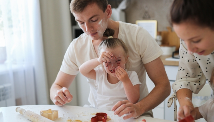 Girl with Down syndrome and dad and family preparing cookies in the kitchen,