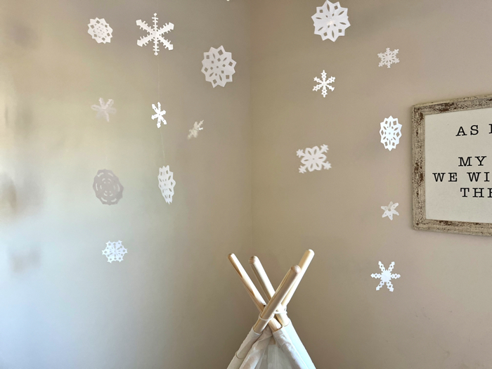 Hanging paper snowflakes above an indoor teepee.