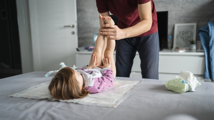 Father change diapers to his daughter toddler in bedroom.