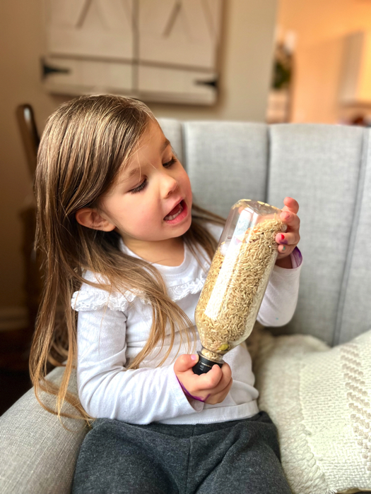 Little girl playing with a winter-themed I spy sensory bottle.