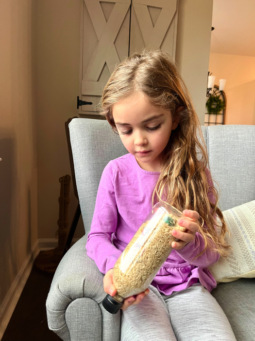 Little girl playing with a winter-themed I spy sensory bottle.