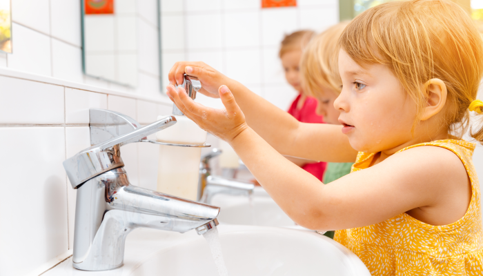 Child in kindergarten washing her hands in bathroom.