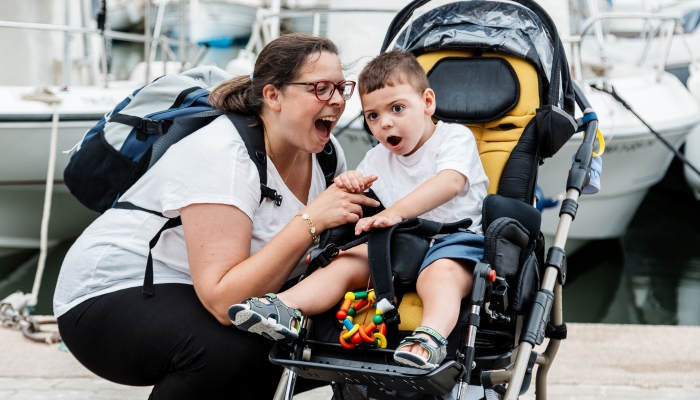 Child with a pluri disability, in an adapted stroller.