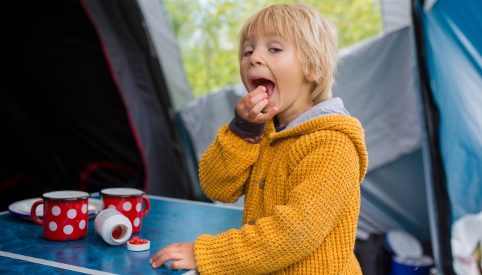 Cute little toddler boy, eating vitamins on a family holiday.