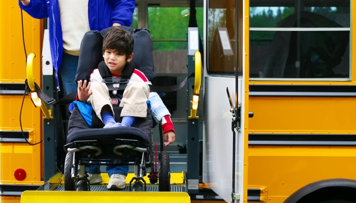 Disabled five year old boy using a bus lift for his wheelchair.