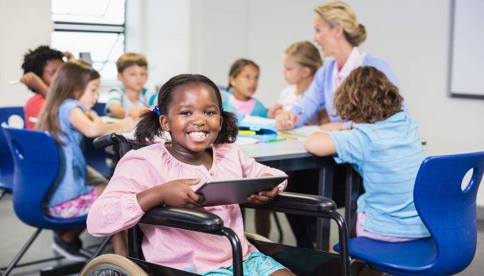 Disabled schoolgirl using digital tablet in classroom at school.