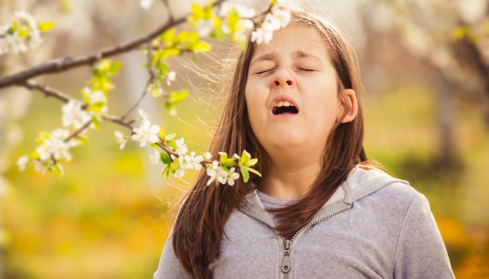 Girl having allergy outdoor, sneezing.