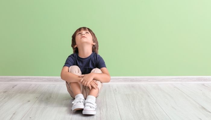 Little boy with autistic disorder near color wall.