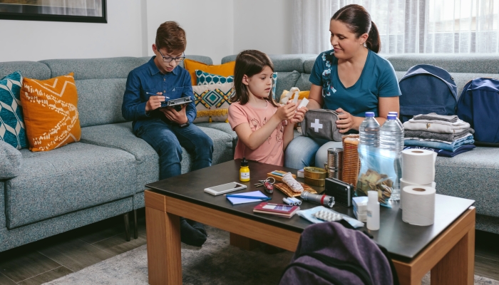 Mother preparing emergency backpack with her children in the living room.