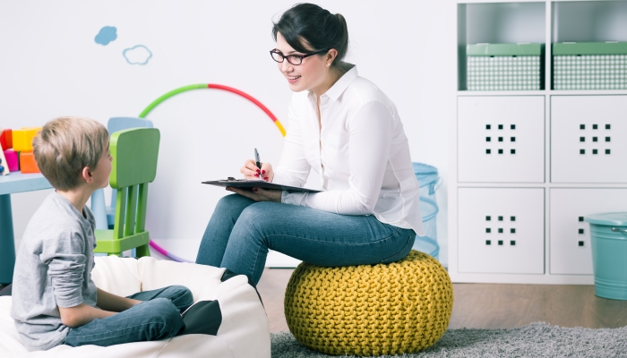 Shot of a young child psychologist talking with a boy.