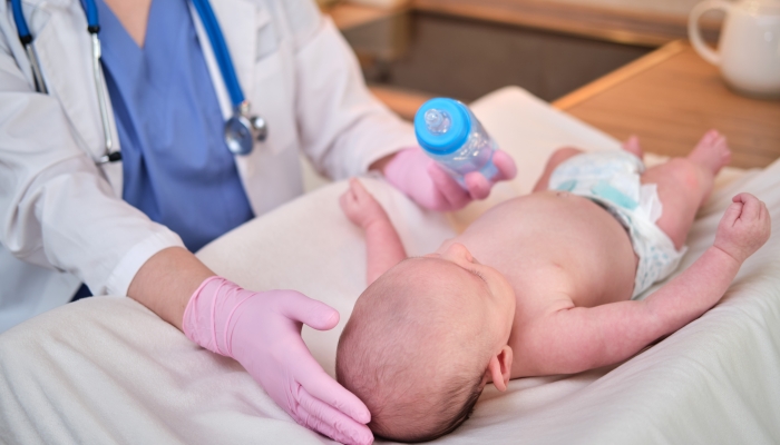 Woman doctor feeding a newborn baby from a bottle.