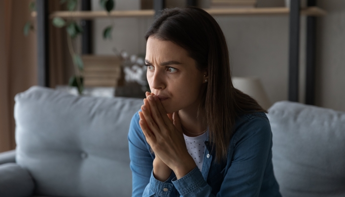 Worried young woman sit on sofa.