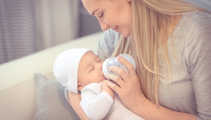 Young mother feeding her little precious baby from the bottle.