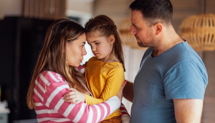 Young parents comfort their cute daughter.