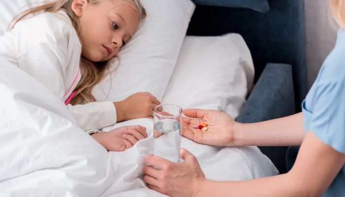 Cropped shot of mother giving pills and water to her sick daughter.