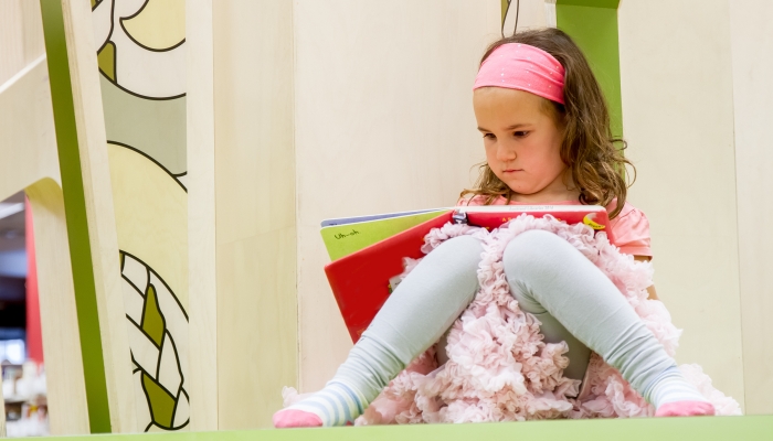 Portrait of young happy child girl reading a book.