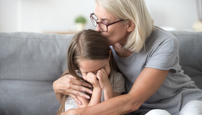 Attractive middle aged woman embrace little preschool frustrated kid sitting on couch together at home.