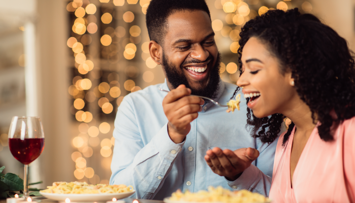 Beautiful young african american couple in love sitting in cafe and eating dinner.