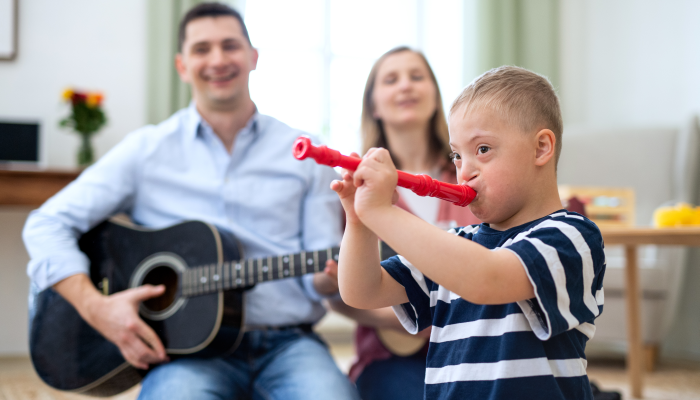 Cheerful down syndrome boy with parents playing musical instruments, laughing.