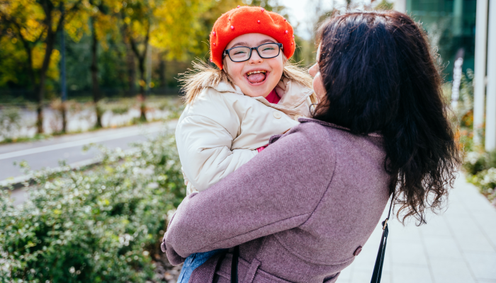 Cute little girl in a red beret with special needs enjoy having fun spending time with mother outdoor in aututm time.