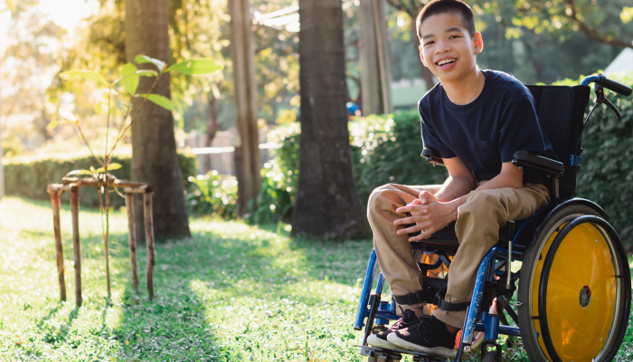 Disabled child on wheelchair is playing, learning and exercise in the outdoor city park.