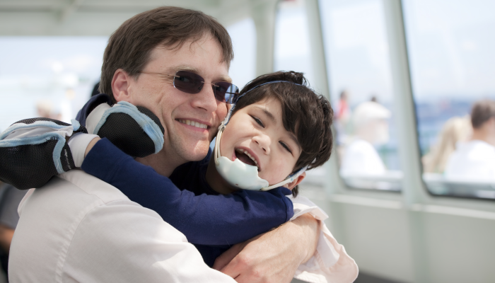 Father hugging disabled son as they ride a ferry boat.